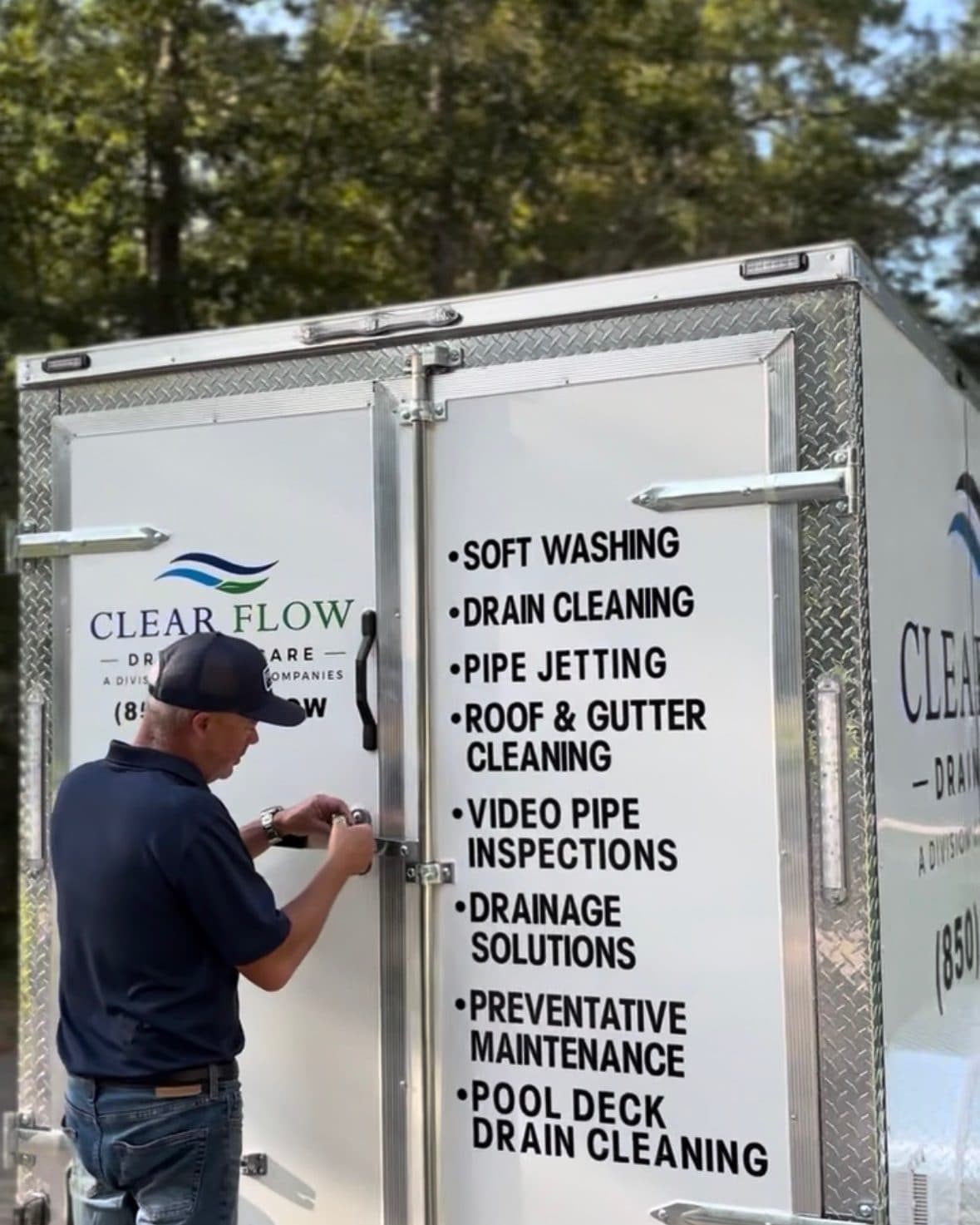 Two Clear Flow technicians setting up at the back of the Clear Flow trailer before a job